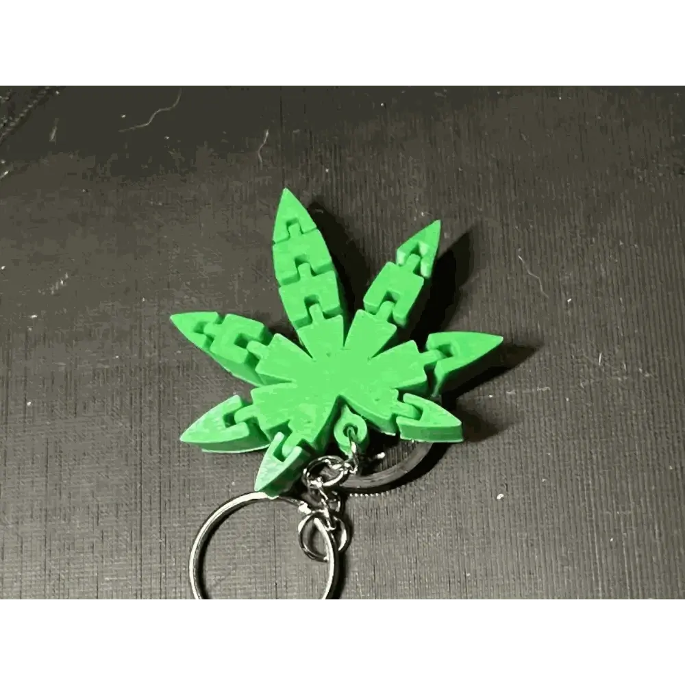 Custom 3D-printed keychain in a green, leaf-shaped design on a black background.